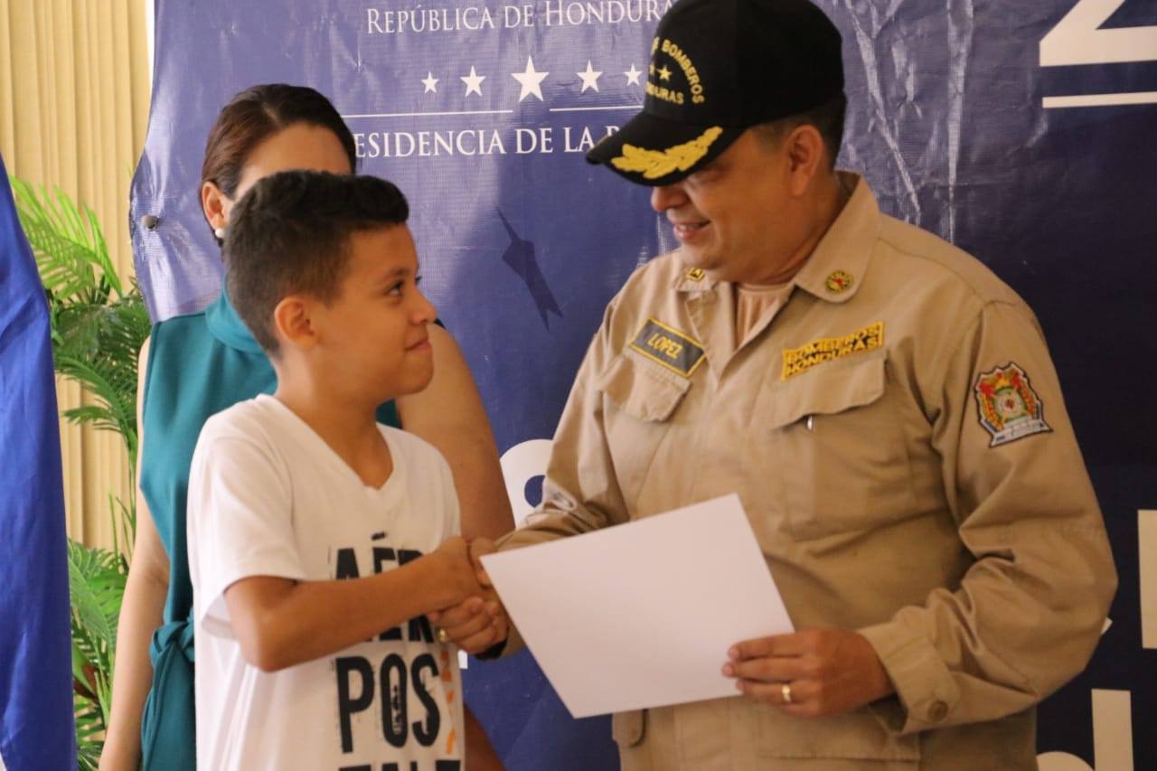 Hijos de bomberos fallecidos en tragedia en La Montañita reciben beca 20/20