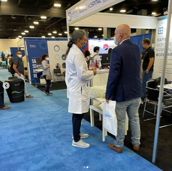 hombre vestido con bata blanca ofrece productos medicos en feria de miami 