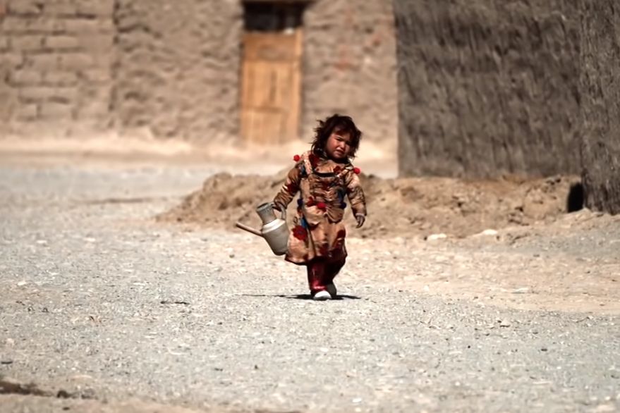 Niña en Afganistán con un recipiente de agua.