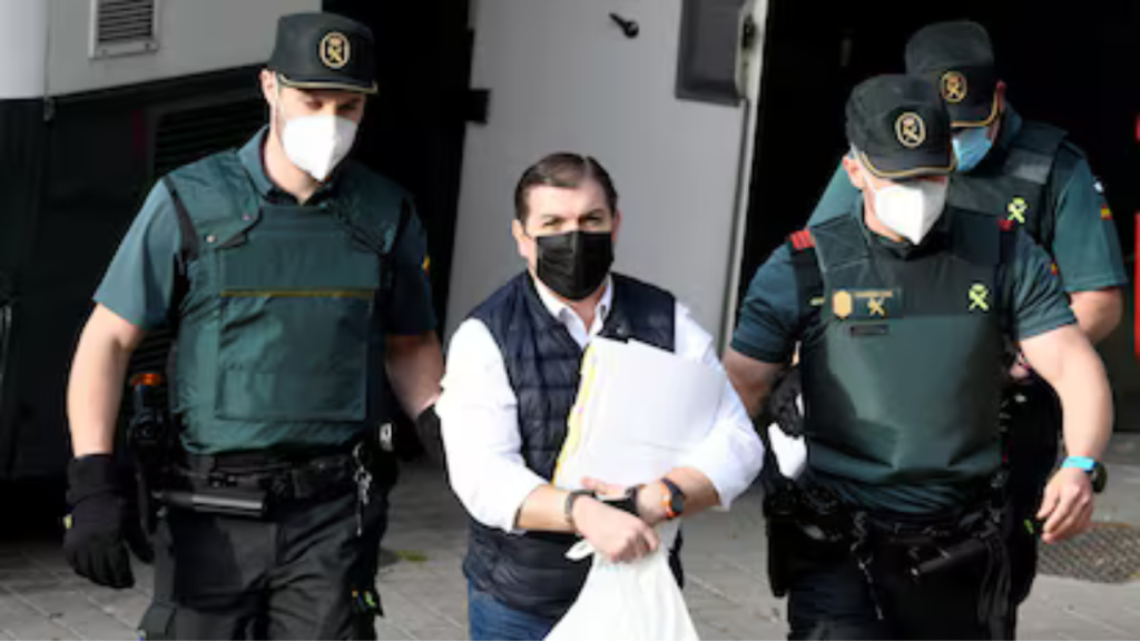 César Román en medio de dos hombre cuando fue capturado