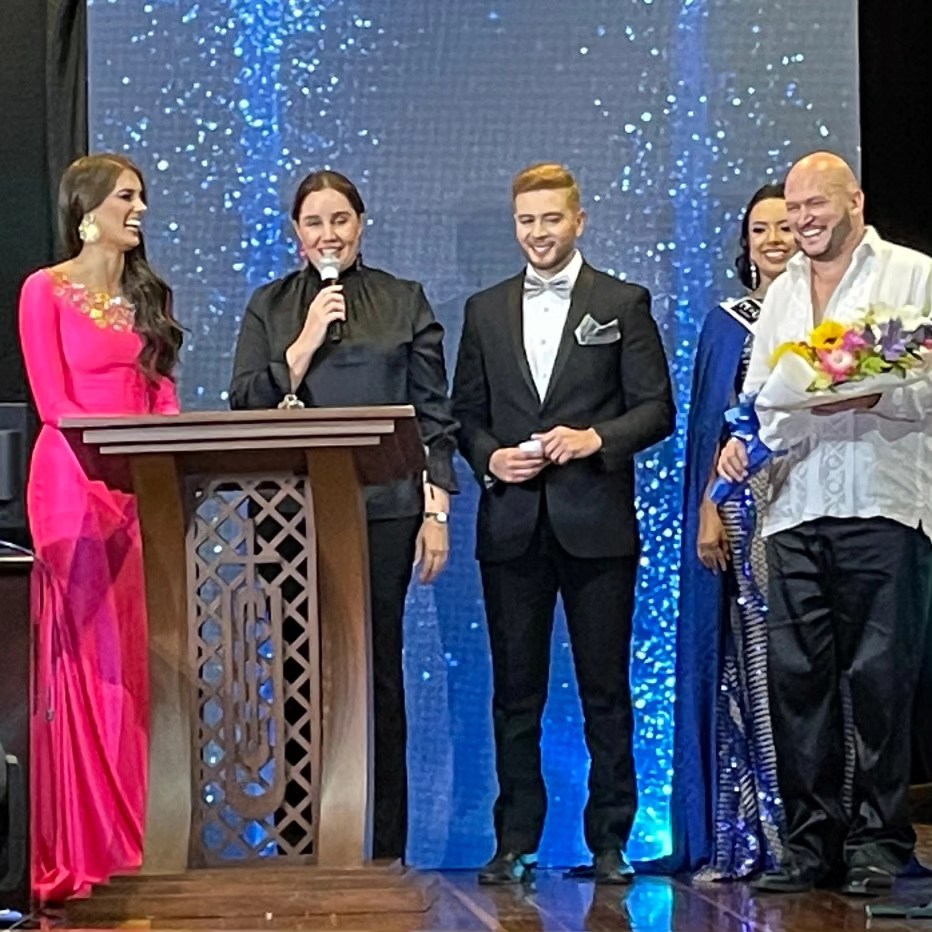 Carlos Miranda de pie sosteniendo un ramo de flores junto a otras cuatro personas