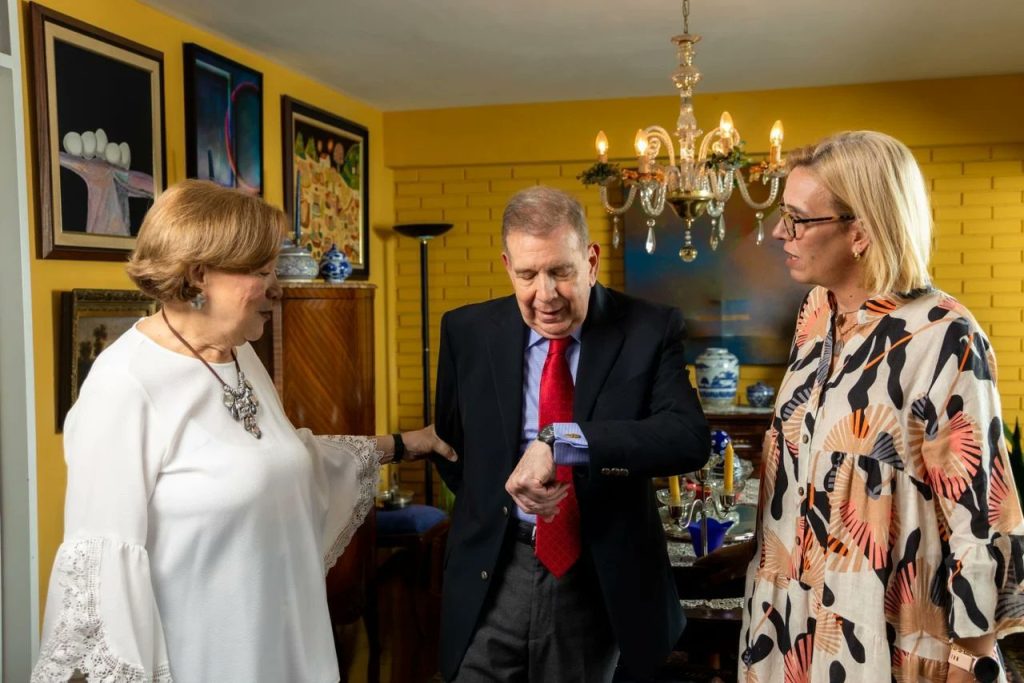 Edmundo González viendo su reloj mientras su esposa está a la izquierda y su hija a la derecha