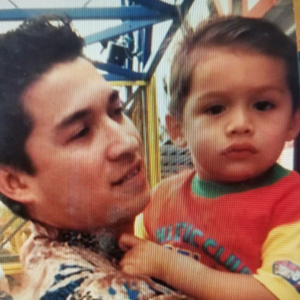 David Castañeda de niño viendo al frente mientras es cargado por su padre