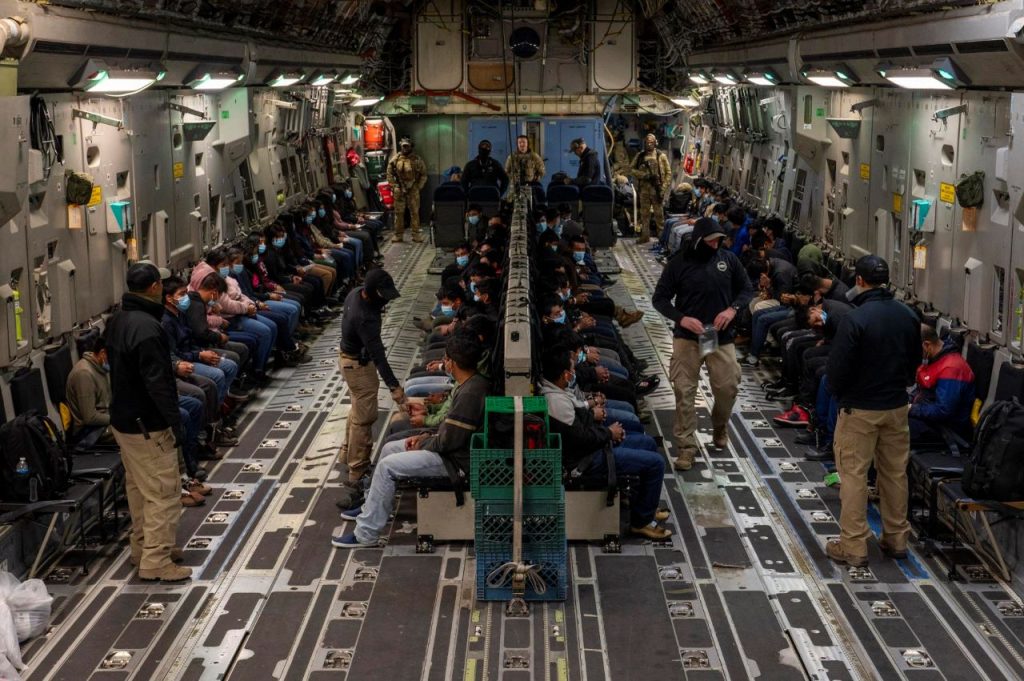 Interior de un avión militar con personas que van deportadas