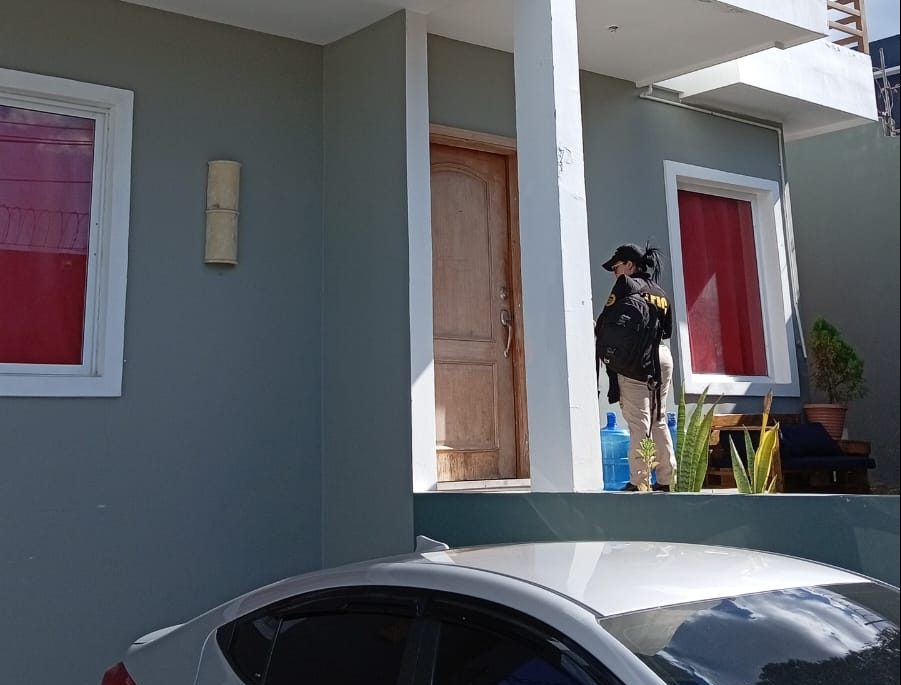 Una agente de la ATIC en la entrada de una casa