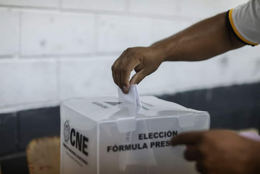 Una mano poniendo un voto en una urna