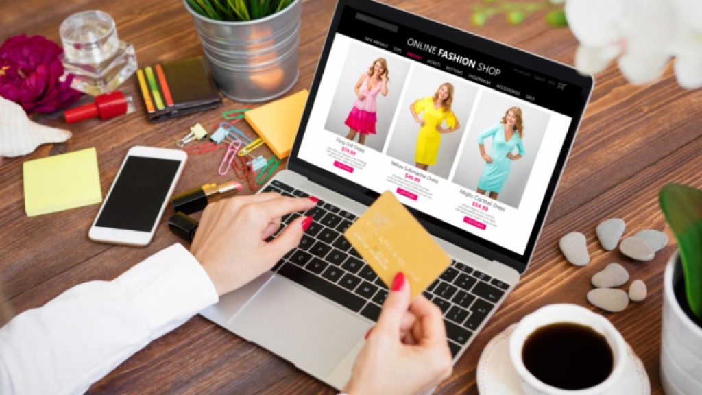 Una persona detrás de una computadora con una tarjeta de crédito en su mano