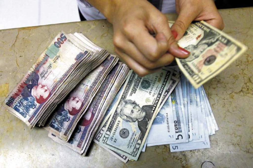 Una persona con dólares y lempiras