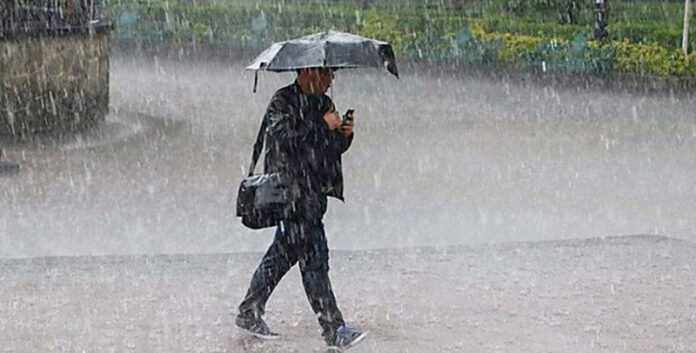 Una persona con paraguas caminando bajo la lluvia