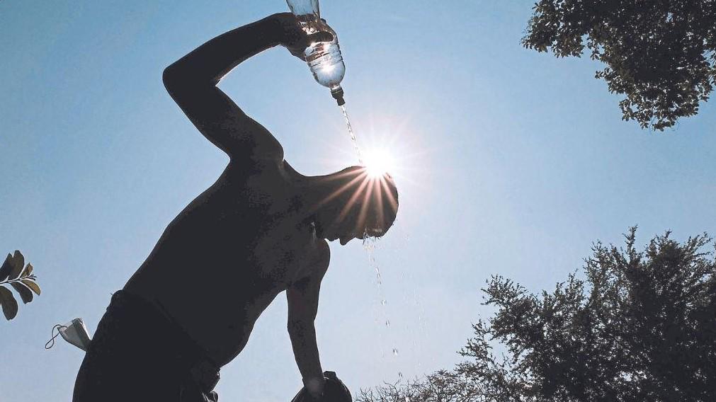 Una persona poniéndose agua bajo el sol