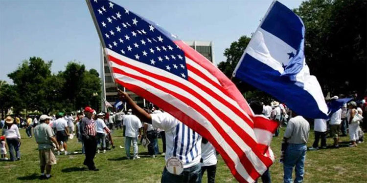 Personas levantando la bandera de Honduras y Estados Unidos