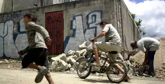 Niños jugando cerca de una casa con dibujos de maras