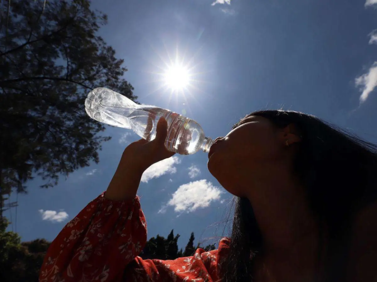Una mujer tomando agua bajo el sol