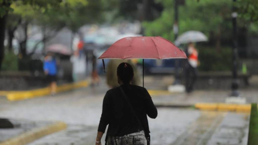 Una mujer con paraguas caminando bajo lluvias